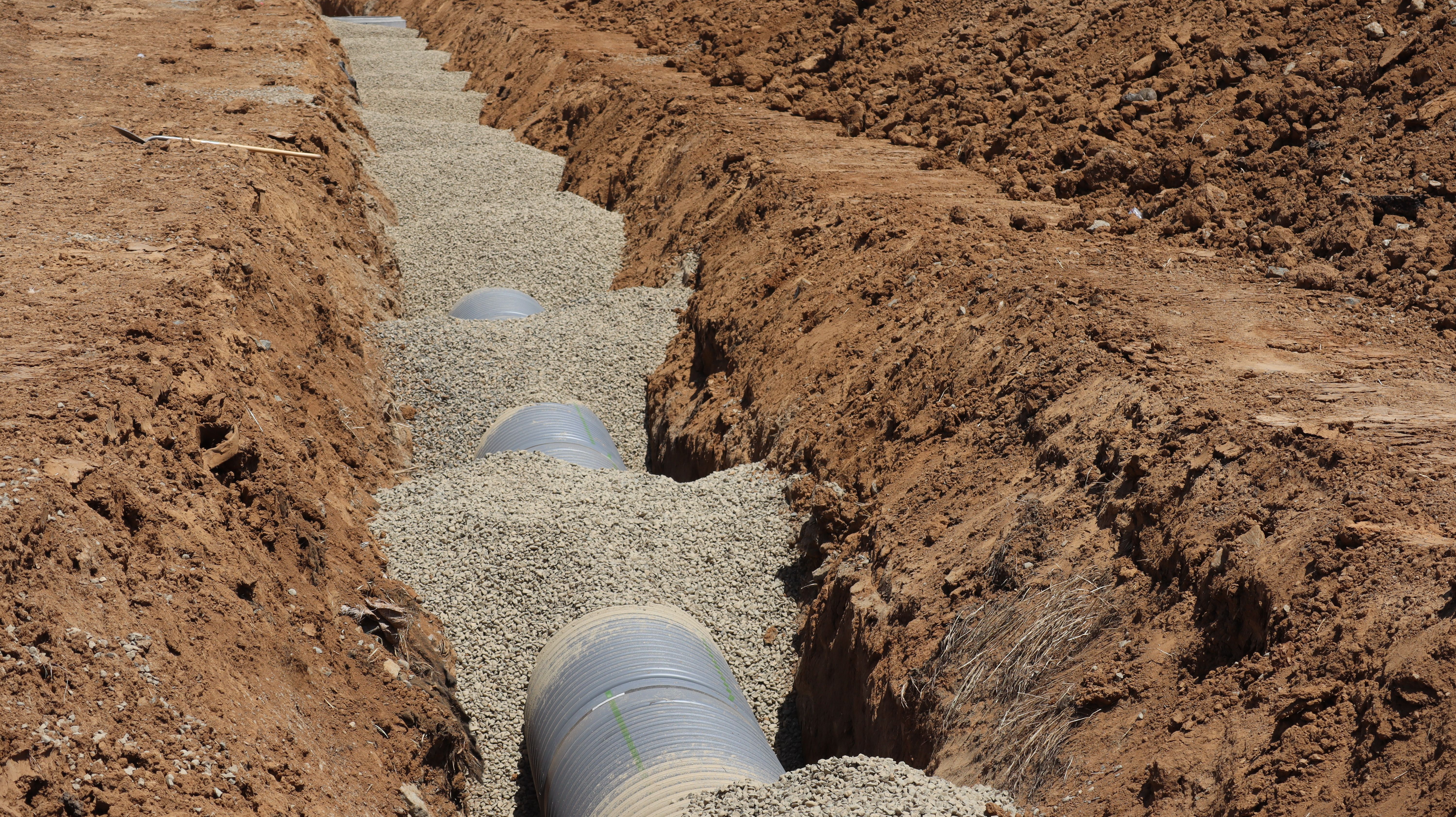 Drainage pipes set in a gravel bed during trench installation